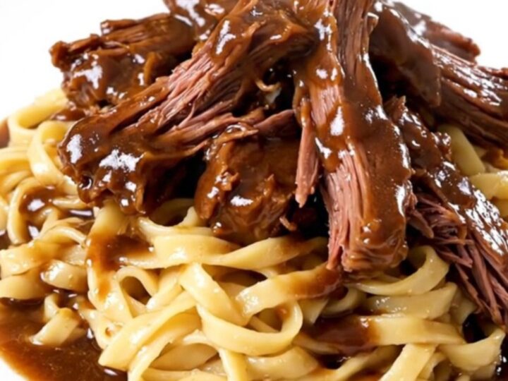 A steaming plate of tender Crockpot Burgundy Beef Tips served over a generous portion of egg noodles.