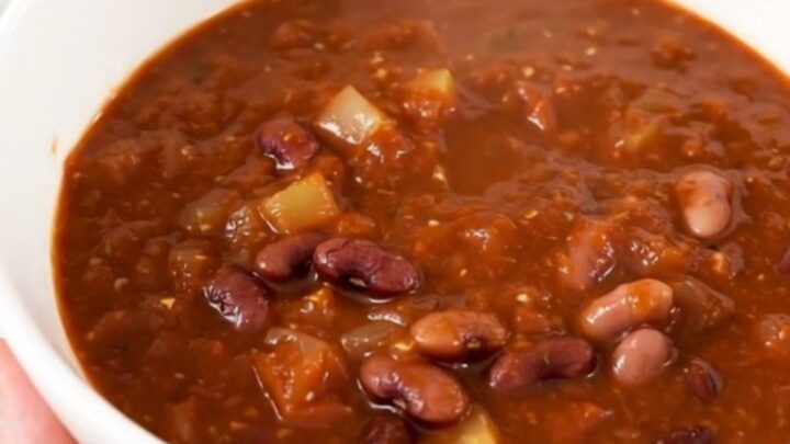 A steaming bowl of Southwest three bean chili served in a white bowl on a kitchen counter.