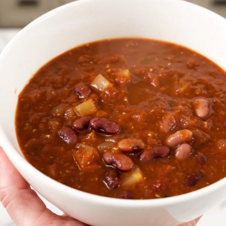 A steaming bowl of Southwest three bean chili served in a white bowl on a kitchen counter.