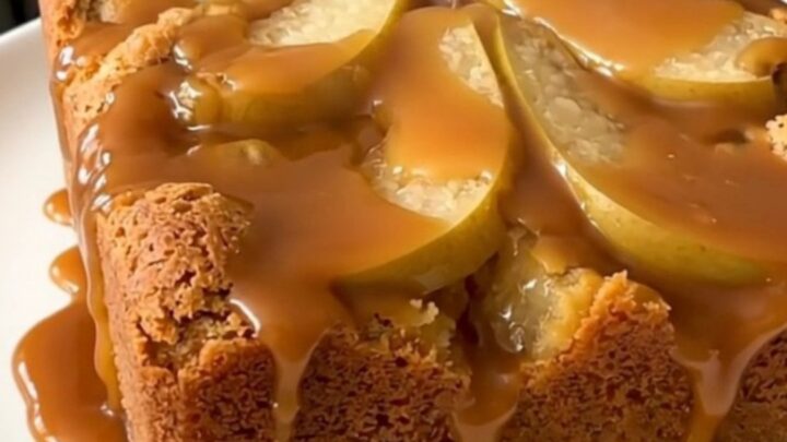 A warm, golden brown slow cooker pear dump cake with visible caramel sauce and walnuts.