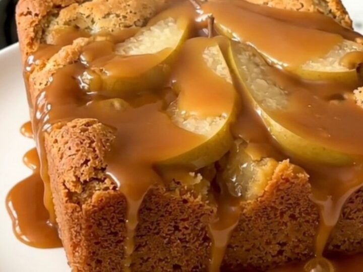 A warm, golden brown slow cooker pear dump cake with visible caramel sauce and walnuts.