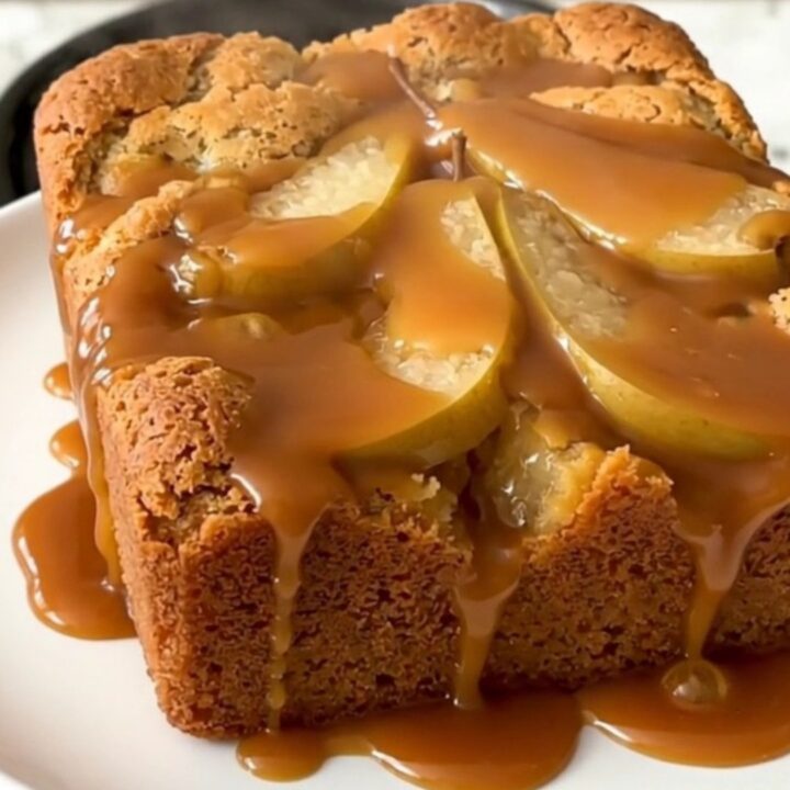 A warm, golden brown slow cooker pear dump cake with visible caramel sauce and walnuts.