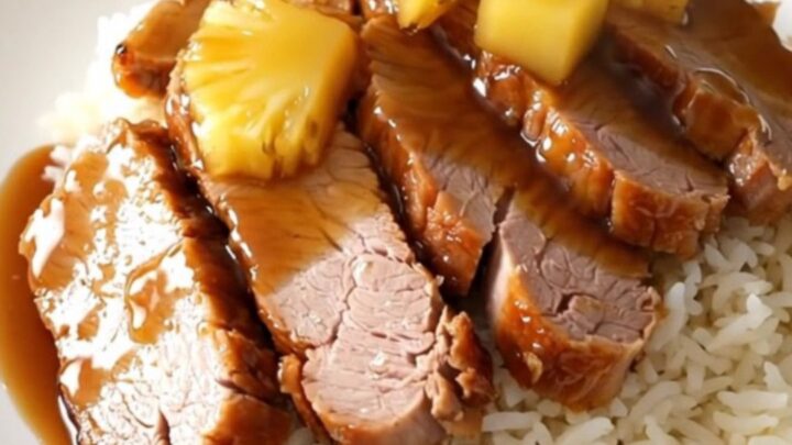Glazed pineapple teriyaki pork loin sliced on a white plate with rice.