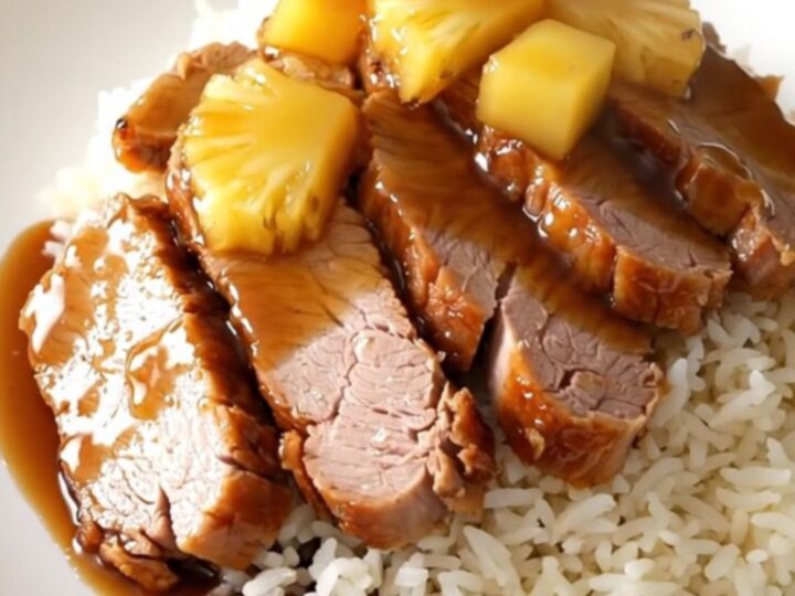 Glazed pineapple teriyaki pork loin sliced on a white plate with rice.