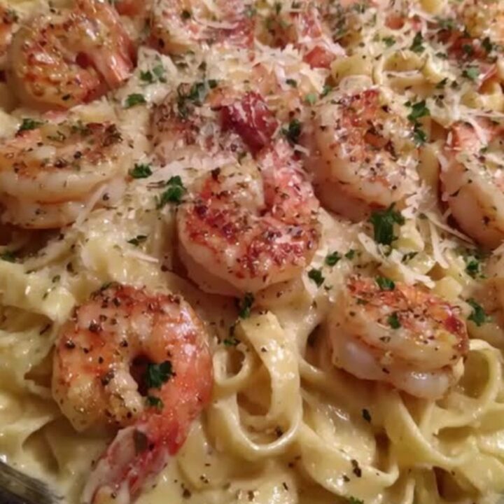 A skillet of creamy shrimp fettuccine alfredo garnished with freshly cracked black pepper and chopped parsley