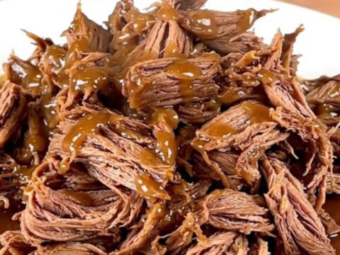 A close-up of tender, shredded maple bacon chuck roast served on a white plate.