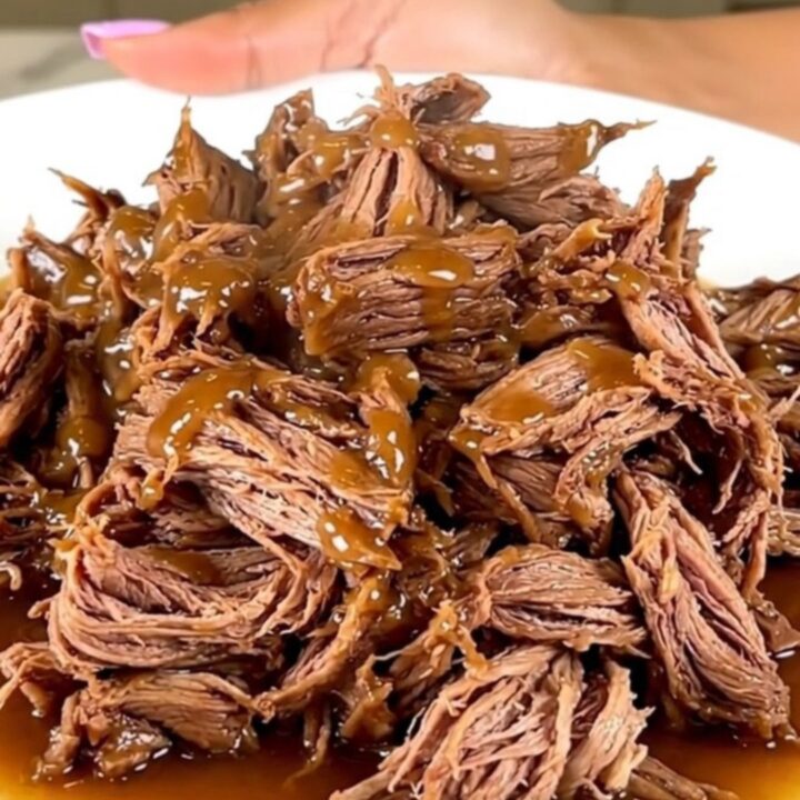 A close-up of tender, shredded maple bacon chuck roast served on a white plate.
