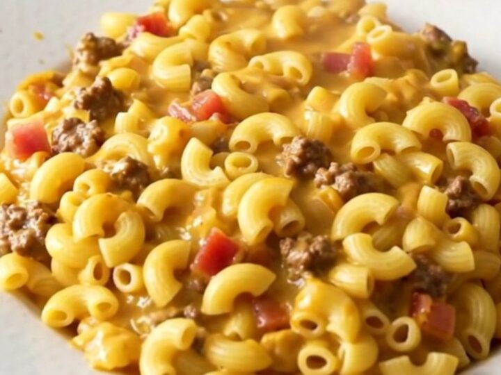 A steaming, glossy portion of slow cooker bacon cheeseburger macaroni casserole served on a white plate.