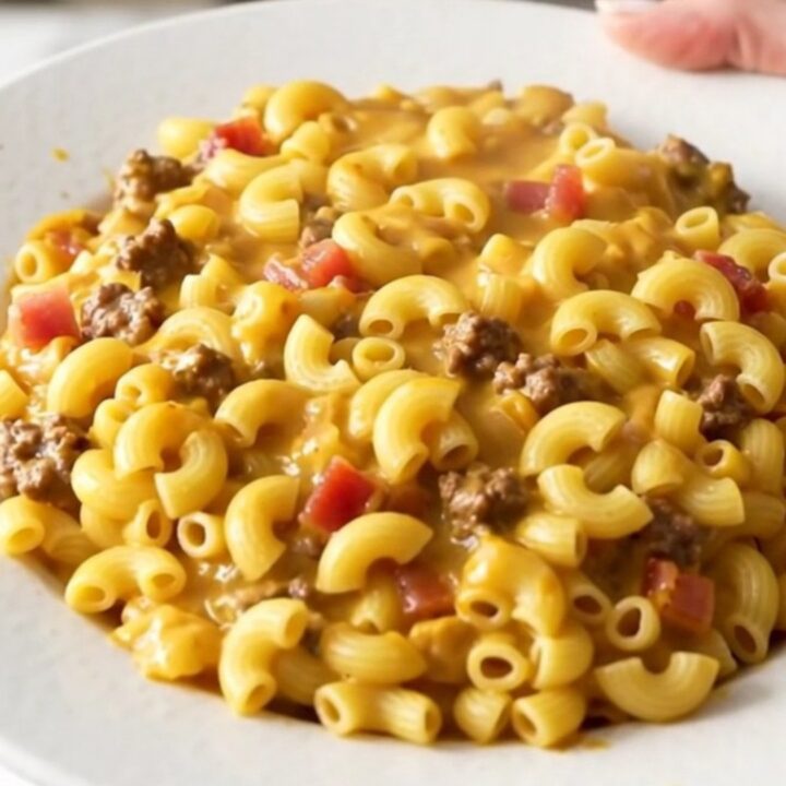 A steaming, glossy portion of slow cooker bacon cheeseburger macaroni casserole served on a white plate.