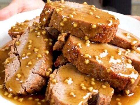A close-up of sliced honey mustard pork tenderloin on a white plate with a glossy glaze.