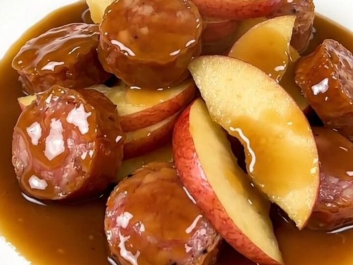 A close-up of finished maple Dijon smoked sausage and tender apple slices served on a white plate.