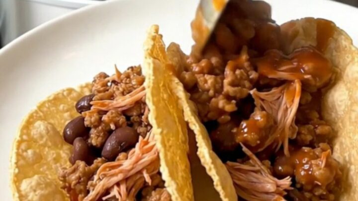 A top-down view of a slow cooker filled with raw ground turkey, black beans, and tomato sauce ready for cooking.