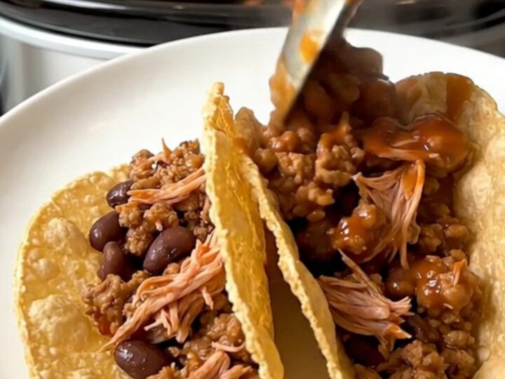 A top-down view of a slow cooker filled with raw ground turkey, black beans, and tomato sauce ready for cooking.