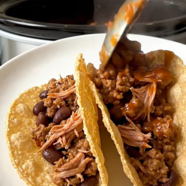 A top-down view of a slow cooker filled with raw ground turkey, black beans, and tomato sauce ready for cooking.