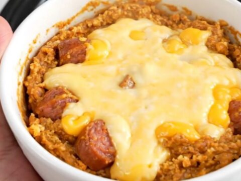 A bowl of hot, creamy spicy sausage queso dip with melted cheese and visible bits of sausage and tomatoes.