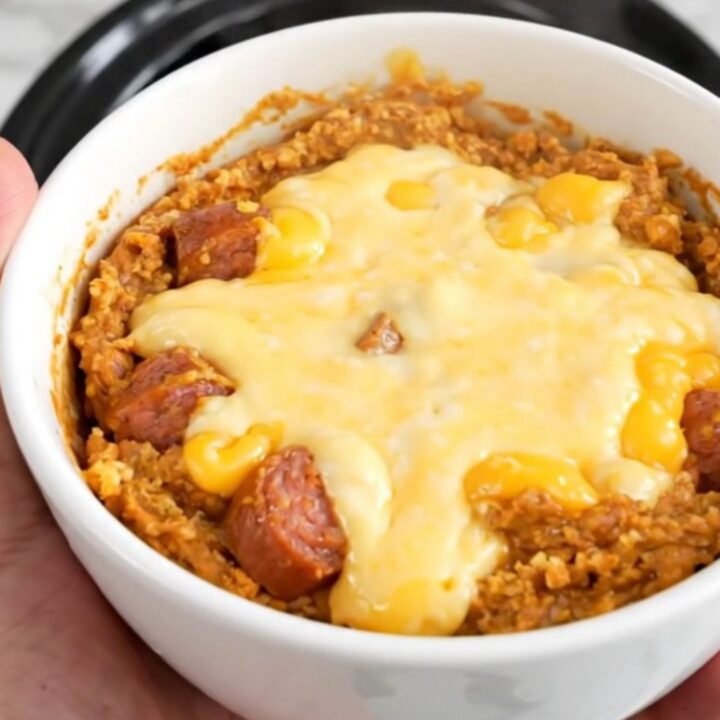 A bowl of hot, creamy spicy sausage queso dip with melted cheese and visible bits of sausage and tomatoes.