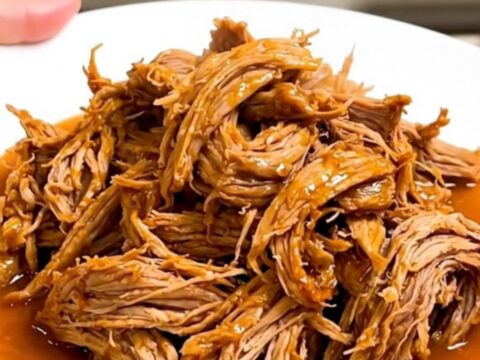 A slow cooker filled with tender, shredded citrus pork ready for serving.