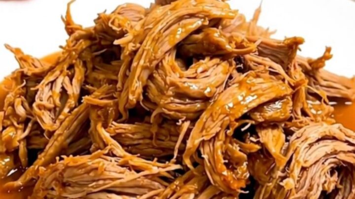 A slow cooker filled with tender, shredded citrus pork ready for serving.