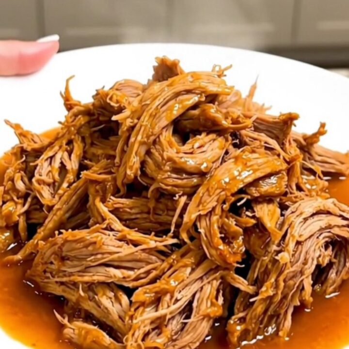 A slow cooker filled with tender, shredded citrus pork ready for serving.