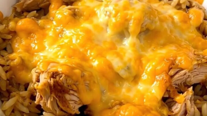 A slow cooker filled with chicken, rice, and salsa verde, topped with melted cheese.