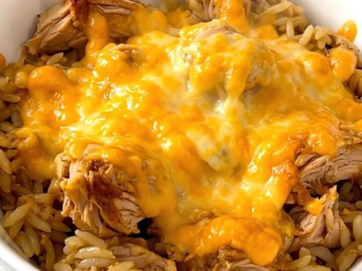 A slow cooker filled with chicken, rice, and salsa verde, topped with melted cheese.