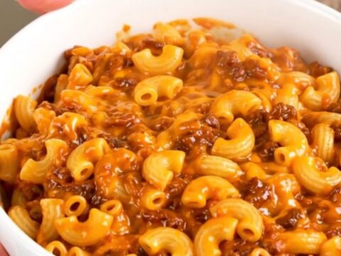 A steaming, hearty bowl of homemade chili mac and cheese in a white bowl, ready to eat.