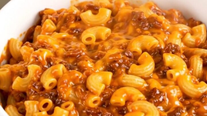 A steaming, hearty bowl of homemade chili mac and cheese in a white bowl, ready to eat.
