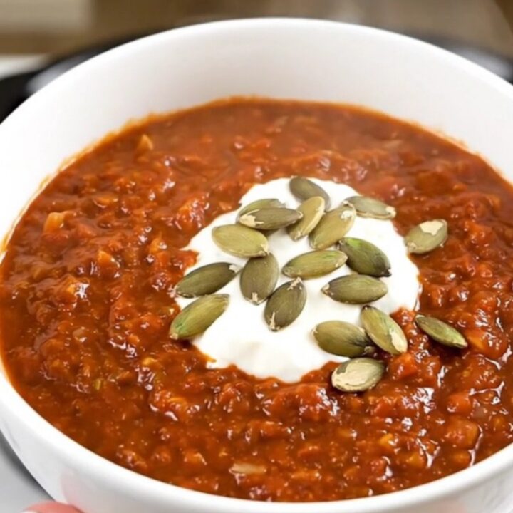 A top-down view of a black ceramic slow cooker filled with ingredients for ground turkey chili.