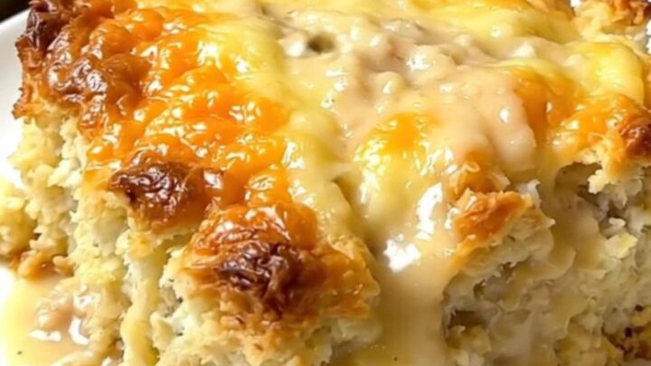A steaming, golden-brown breakfast casserole served in a slow cooker with visible layers of biscuits and sausage.