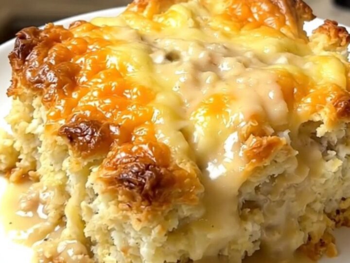 A steaming, golden-brown breakfast casserole served in a slow cooker with visible layers of biscuits and sausage.