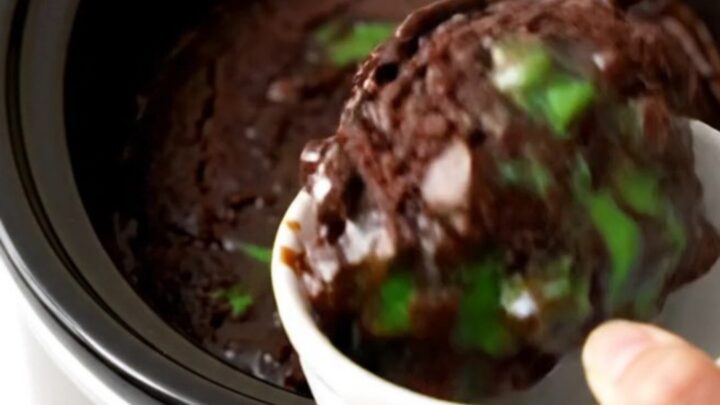A warm, glossy dark chocolate mint dump cake in a slow cooker with visible melted chips.