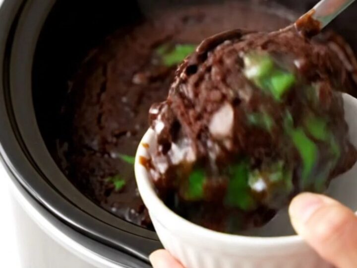 A warm, glossy dark chocolate mint dump cake in a slow cooker with visible melted chips.