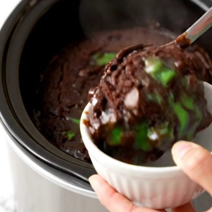 A warm, glossy dark chocolate mint dump cake in a slow cooker with visible melted chips.