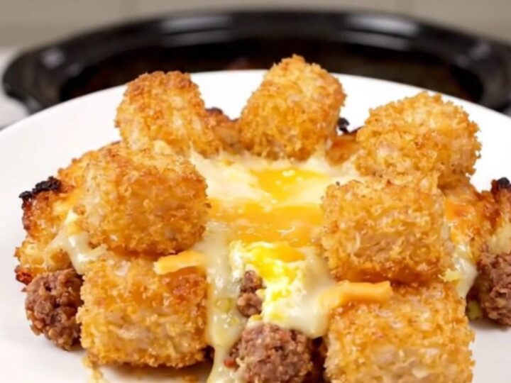 A hearty breakfast casserole in a slow cooker filled with golden tater tots, sausage, melted cheese, and eggs.