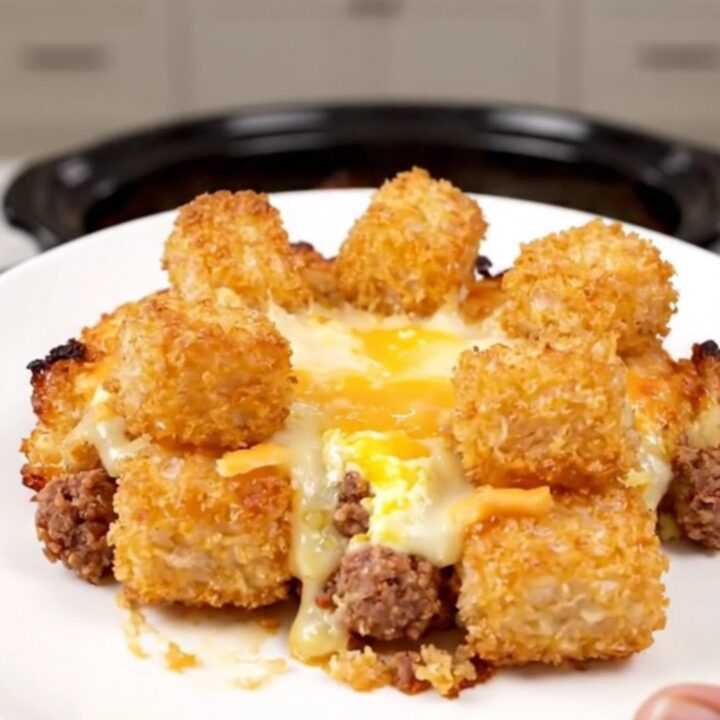 A hearty breakfast casserole in a slow cooker filled with golden tater tots, sausage, melted cheese, and eggs.