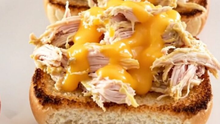A close-up of creamy pimento cheese chicken served on a toasted bun on a white plate.