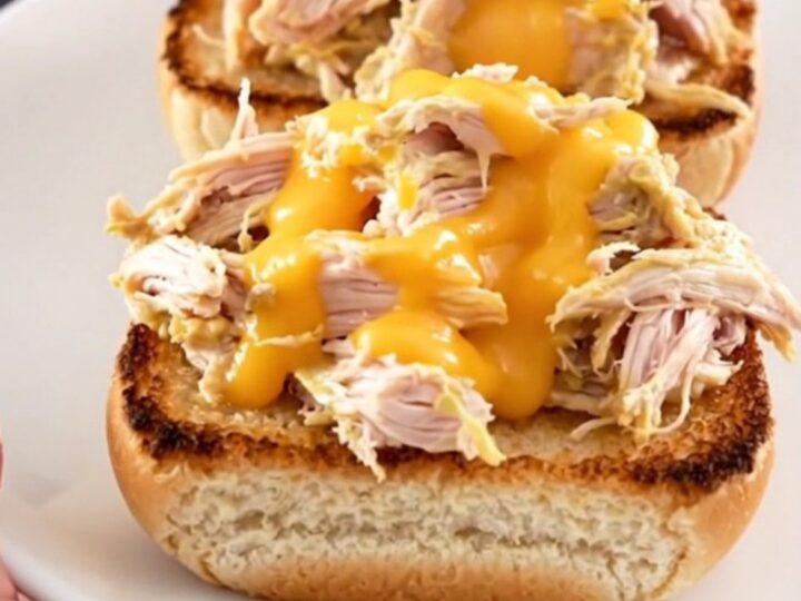 A close-up of creamy pimento cheese chicken served on a toasted bun on a white plate.