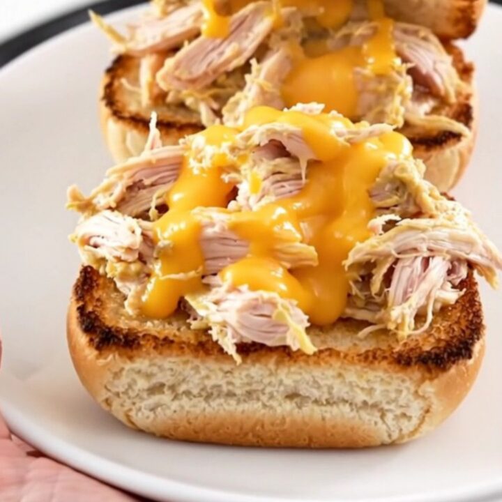 A close-up of creamy pimento cheese chicken served on a toasted bun on a white plate.