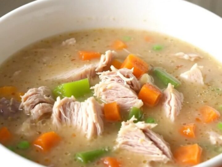 A bowl of creamy turkey pot pie soup with visible chunks of turkey, vegetables, and potatoes.