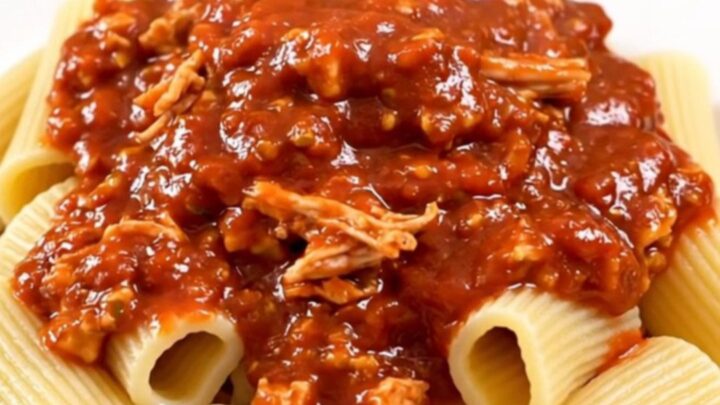 A rustic bowl of slow-cooked turkey bolognese served over rigatoni pasta, topped with fresh herbs.