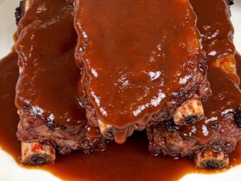 A close-up of glossy, smoky chipotle barbecue ribs on a white plate.