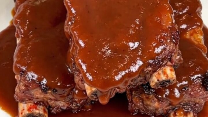 A close-up of glossy, smoky chipotle barbecue ribs on a white plate.