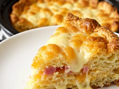 A steaming slice of ham and Swiss breakfast casserole on a white plate.