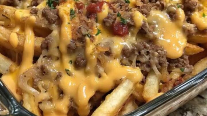 A spatula scooping into a golden cheeseburger french fry casserole, lifting melted cheddar and crispy fries.