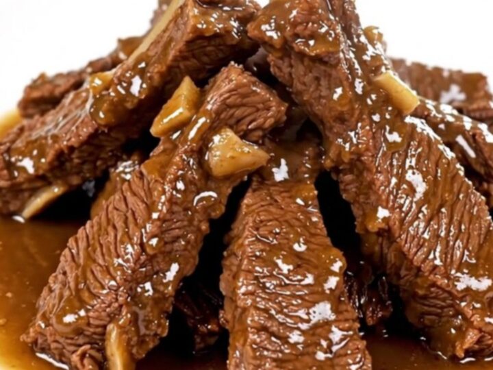A plate of tender, glossy beef tips in a savory herb gravy served on a white plate.