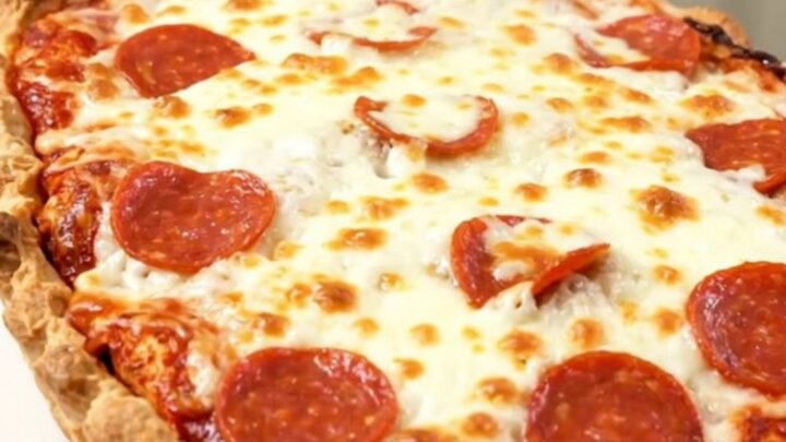 A close-up of a steaming pizza meatball casserole with melted mozzarella and pepperoni in a slow cooker.