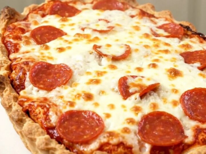 A close-up of a steaming pizza meatball casserole with melted mozzarella and pepperoni in a slow cooker.
