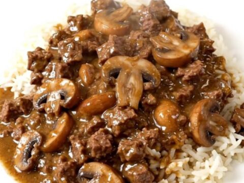A close-up of a hearty creamy beef and mushroom casserole served over a bed of fluffy white rice.