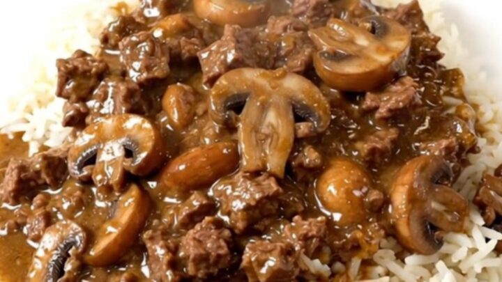 A close-up of a hearty creamy beef and mushroom casserole served over a bed of fluffy white rice.