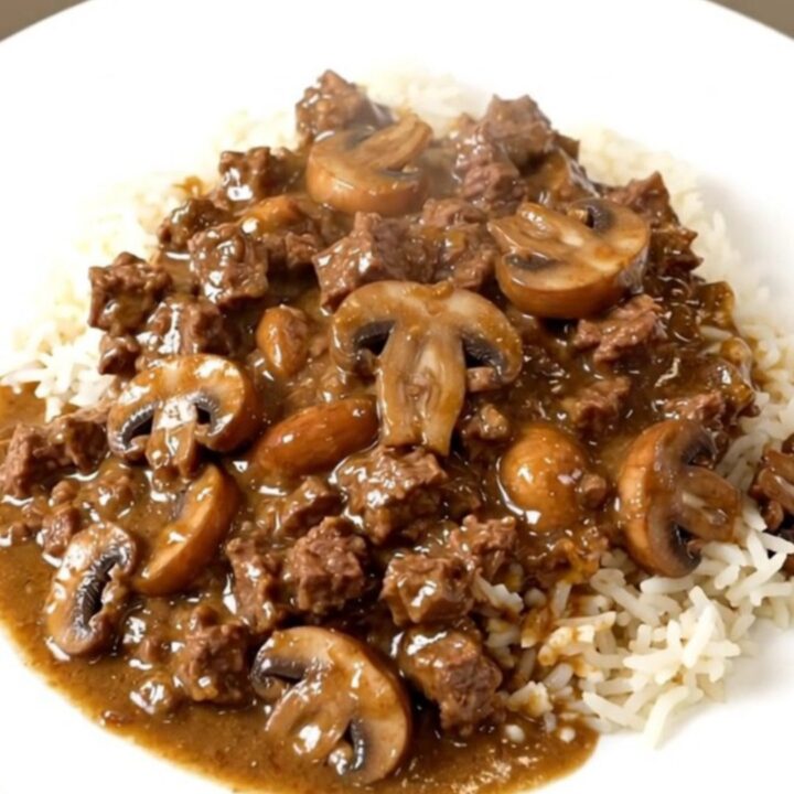 A close-up of a hearty creamy beef and mushroom casserole served over a bed of fluffy white rice.
